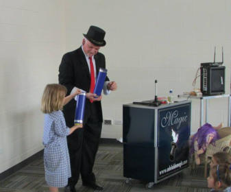 George Stas with a student of a local school performing interactive magic shows